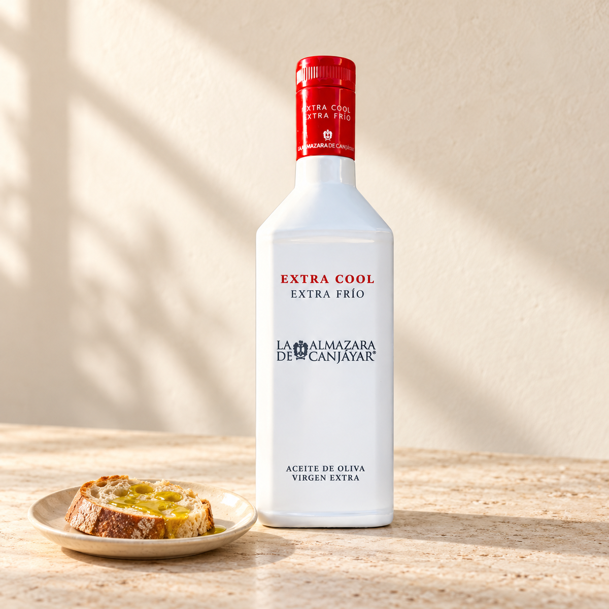 Sticlă de ulei de măsline extravirgin Extra Cool Picual 500 ml, La Almazara de Canjáyar, lângă o felie de pâine cu ulei.