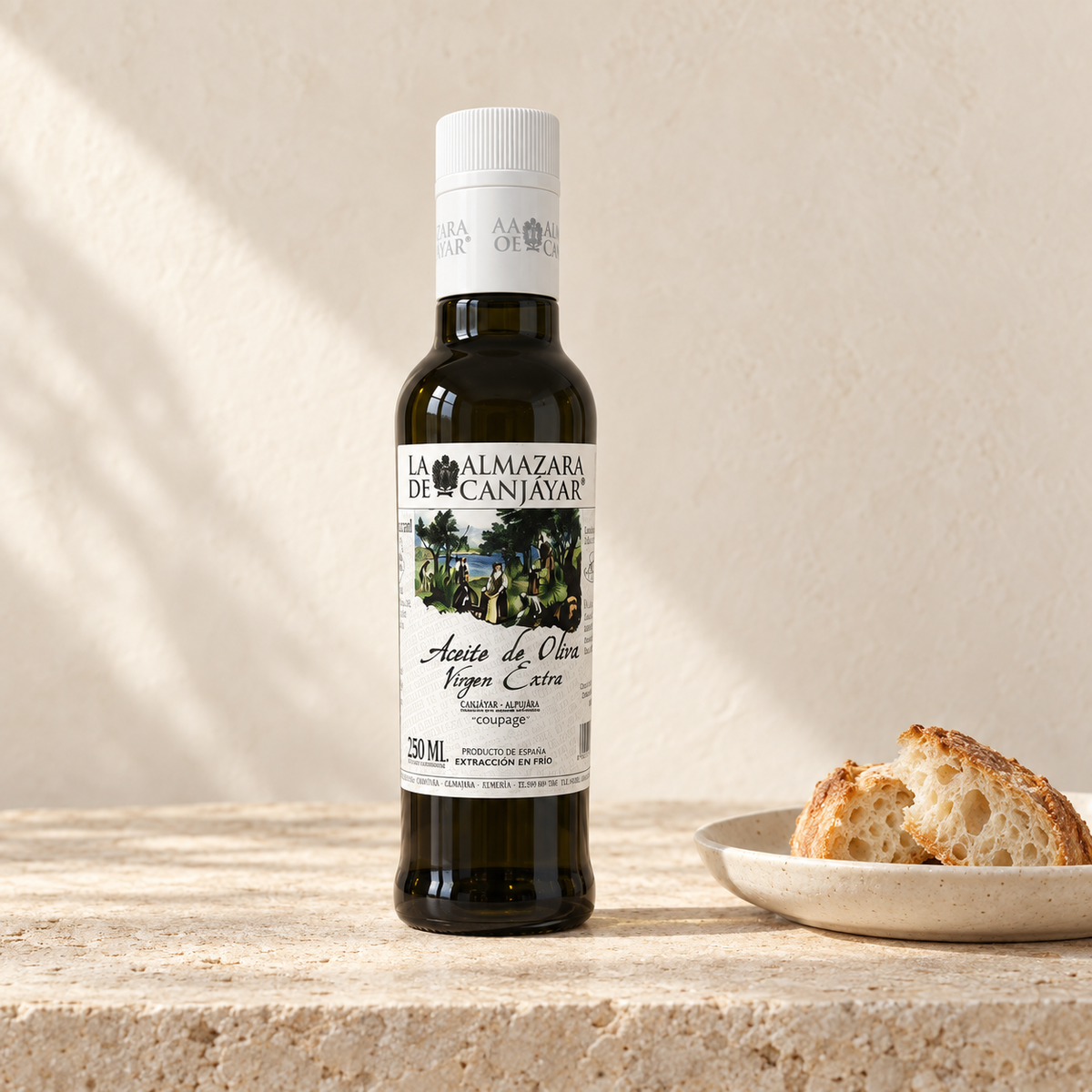 Ulei de măsline extravirgin coupage La Almazara de Canjáyar, 250 ml, pe o masă din piatră bej, lângă o farfurie cu pâine rustică.